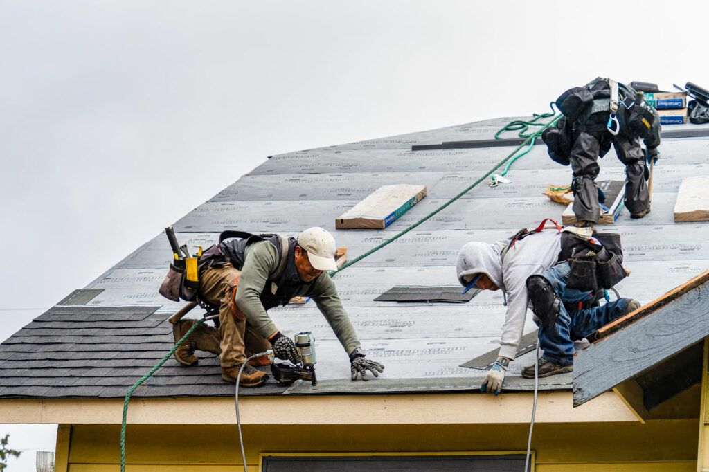 Roofers installing a new roof with asphalt shingles