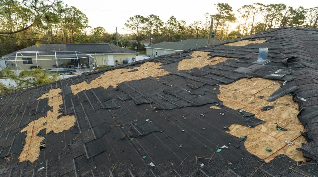 Ruined rooftop in need of repair. Wind damaged house roof with missing asphalt shingles after hurricane Ian in Florida