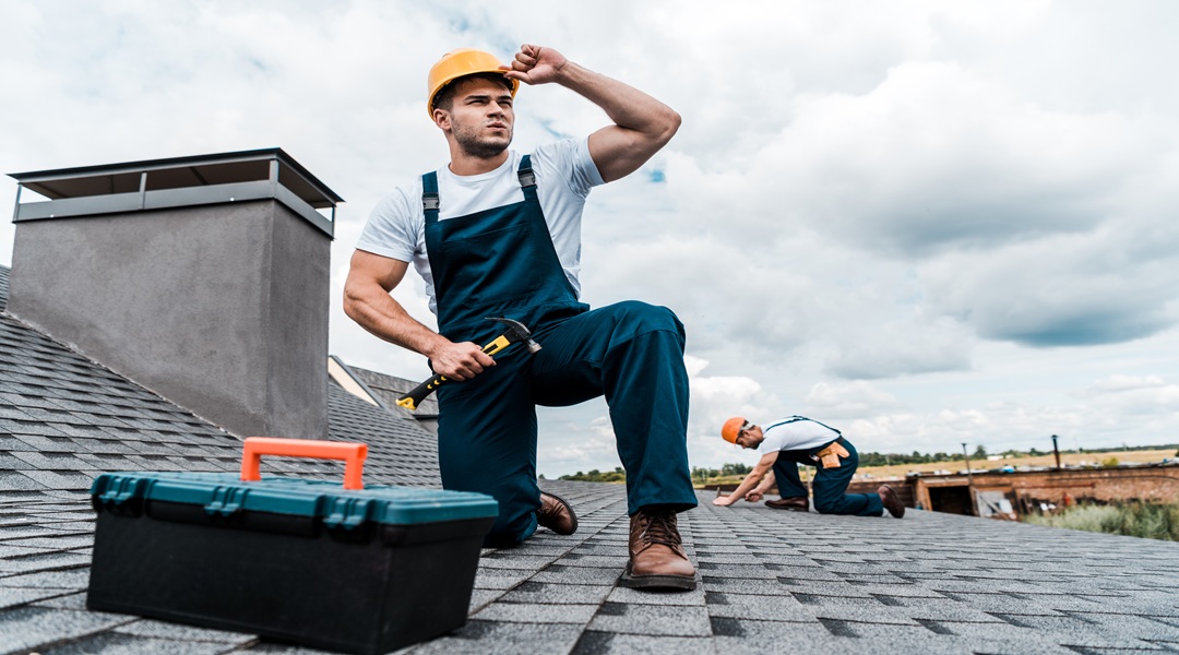 selective focus of handsome handyman touching helmet while holding hammer