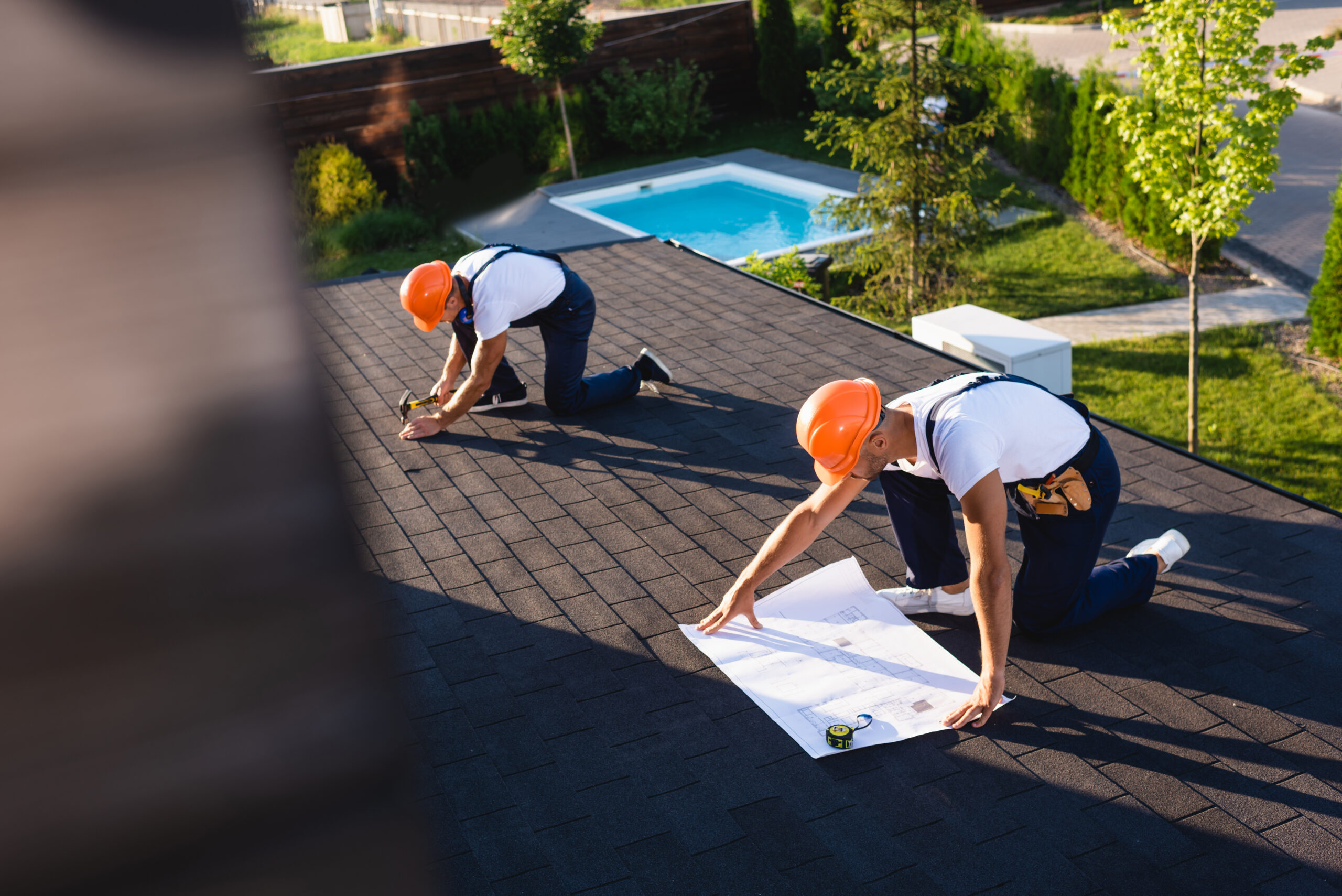 Two roofers working on a residential asphalt shingle roof